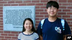 Chinese graduate students Zhaojin Li, left, and Pengfei Liu, pose in front of the entrance to the Robert Larner College of Medicine at the University of Vermont in Burlington, Vermont, Aug. 16, 2019.