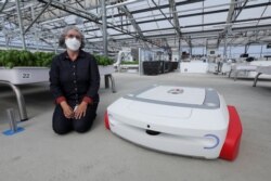 Sarah Osentoski, senior vice president of engineering at Iron Ox, kneels next to the self-driving robot Grover at the Silicon Valley company's greenhouse in Gilroy, California, U.S. on September 15, 2021. REUTERS/Nathan Frandino