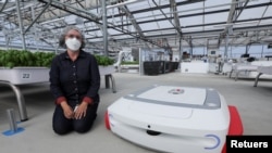 Sarah Osentoski, senior vice president of engineering at Iron Ox, kneels next to the self-driving robot Grover at the Silicon Valley company's greenhouse in Gilroy, California, U.S. on September 15, 2021. REUTERS/Nathan Frandino