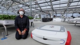 Sarah Osentoski, senior vice president of engineering at Iron Ox, kneels next to the self-driving robot Grover at the Silicon Valley company's greenhouse in Gilroy, California, U.S. on September 15, 2021. REUTERS/Nathan Frandino