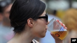 FILE - A woman is seen drinking a beer.
