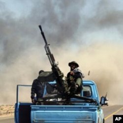 A rebel fighter sits on a truck as he fires an anti-aircraft gun during an air strike at a rebel fighters checkpoint in Al Ugaila area along a road between the towns of Brega and Ras Lanuf, March 12, 2011