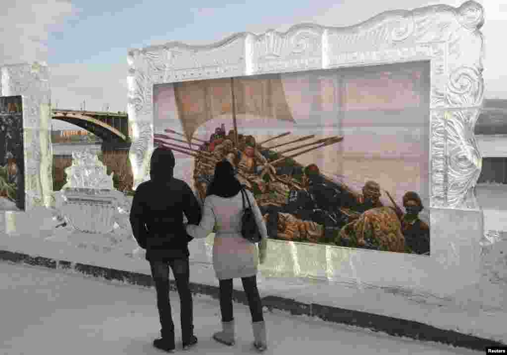 A couple looks at reproductions of work by Russian classical painter Vasily Surikov, displayed in ice frames, during an international festival of snow and ice sculpture called &lsquo;The Magical Ice of the Siberia&rsquo; next to the Yenisei River in Krasnoyarsk, Russia.