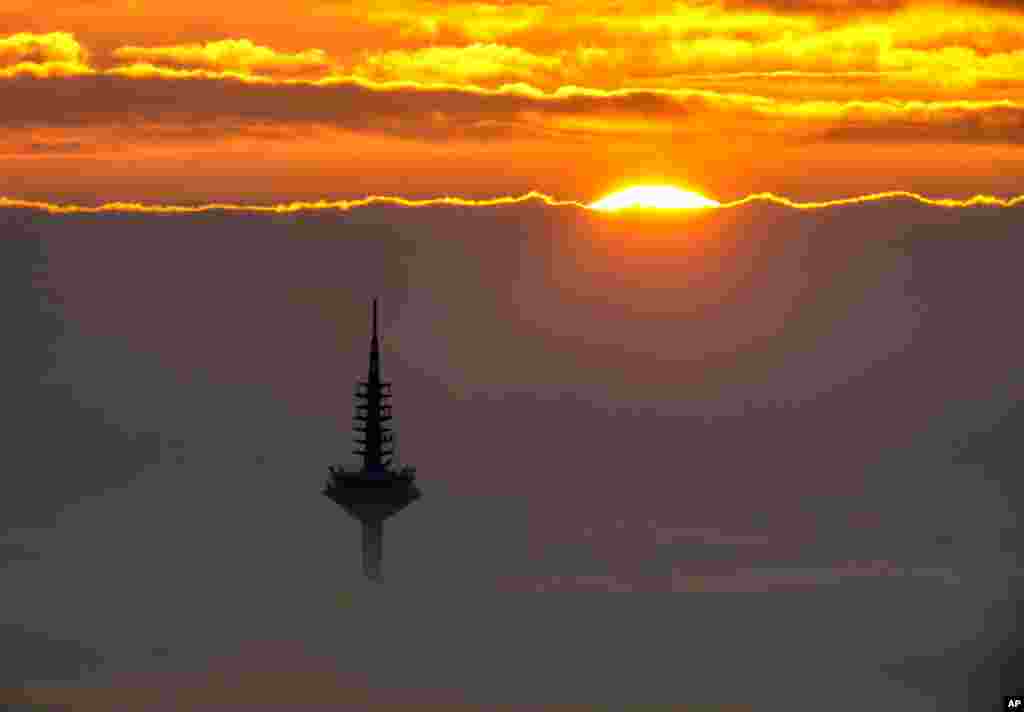 The television tower is seen in the thick fog that covers Frankfurt, Germany, during sunrise, Nov. 6, 2021.