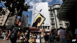 People walk past an advertising billboard for a smartphone in an upscale neighborhood in Istanbul, Turkey, Aug. 15, 2018.