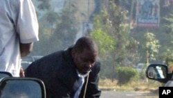 A man believed to be a Kenyan undercover police officer is seen aiming a weapon at men lying on the road in the middle of traffic in Nairobi