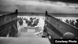  Under withering Nazi fire from the shore, GIs who had just departed their Higgins Boat wade ashore at Normandy. (U.S. Coast Guard)