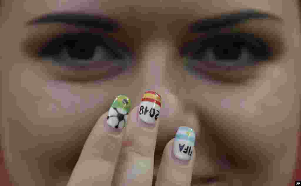 A young woman shows off her painted nails in colors of Brazil, left, Spain and Argentina as she poses for the cameras ahead of the quarterfinal match between Brazil and Belgium at the 2018 soccer World Cup in the Kazan Arena, in Kazan, Russia.