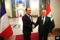Iraq's Prime Minister Haider al-Abadi, right, greets French President Francois Hollande prior to their meeting in Baghdad, Iraq, Jan. 2, 2017.