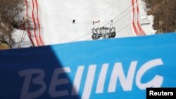 FILE - A staff member skis down a slope during an organized media tour to the National Alpine Skiing Center, a venue of the 2022 Winter Olympic Games, in Beijing's Yanqing district, China, Feb. 5, 2021.