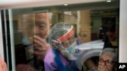 Javier Anto, 90, and his wife Carmen Panzano, 92, blow kisses to one another through the window at a nursing home in Barcelona, Spain.