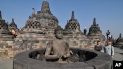 Para turis melihat-lihat patung Buddha di Candi Prambanan di Magelang, Jawa Tengah, 12 Agustus 2019. (Foto: AP/Slamet Riyadi)