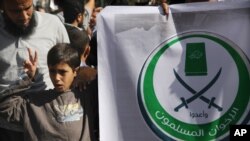 An Egyptian boy holds a banner with Arabic that reads, "Muslim Brotherhood," in Cairo, Egypt, Nov. 15, 2012.