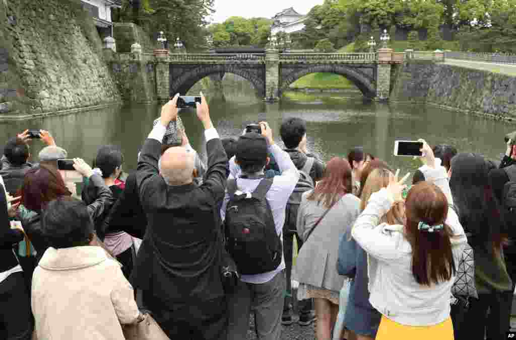 مردم خروج امپراتور سابق ژاپن و ورود امپراتور جدید را به کاخ با دوربین های شان ثبت می کنند.&nbsp;