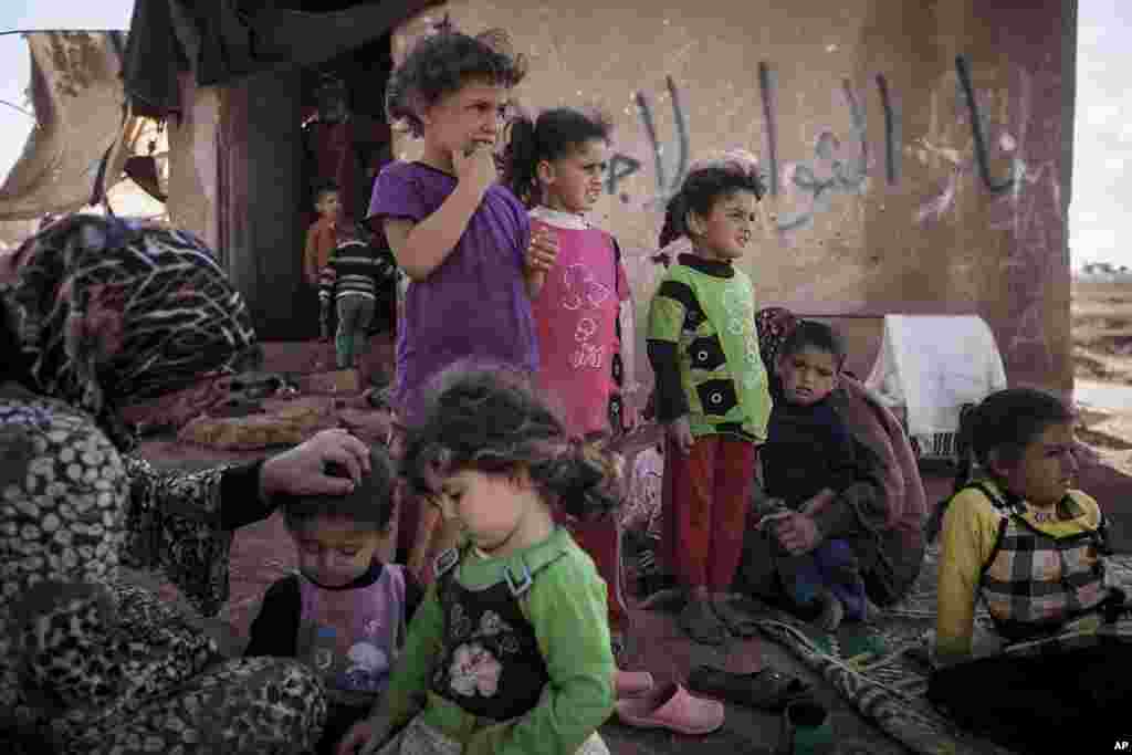 Syrian internally displaced families gather on abandoned land where they have taken shelter after fleeing their village that turned into a battlefield in Idlib province, Sept. 22, 2013.