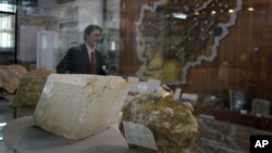 FILE - An Afghan journalist walks by an exhibit of minerals on the way to a news conference by the Afghan Minister of Mines in Kabul, Afghanistan, June 17, 2010