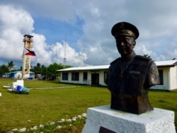 The main town hall of Kalayaan on Thitu Island with the bust of Tomas Cloma, the Filipino marine educator a nd entrepreneur who reportedly discovered the Kalayaan Group of Islands. The lone tower is also seen in the background. (D. Agnote for VOA)