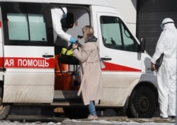 RUSSIA -- Specialists wearing protective mask and suit escort a patient to a multi-specialty hospital complex in the Kommunarka settlement in New Moscow, March 16, 2020