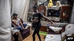 Dance Center Kenya (DCK) student Bravian Mise, 13, (C) shows some dancing moves to his mother Rehema Mwikali, 34, (L) inside their home at the Kuwinda informal settlement in Nairobi on November 27, 2023.