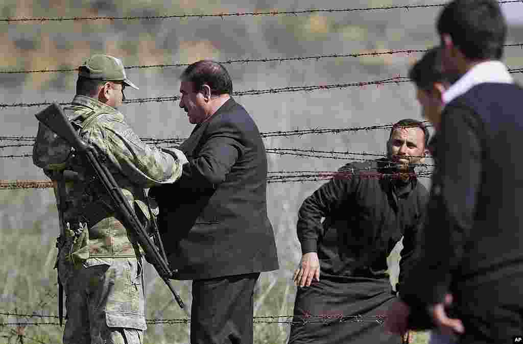 A Turkish soldier, left, watches as Syrians refugees clear a barbed wire fence to flee Syria at a border crossing near Reyhanli, Turkey, March 20, 2012. (AP)
