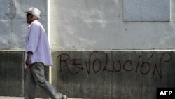 Un hombre pasa frente a un graffiti que dice “Revolución” en un muro de Caracas, Venezuela, el 28 de enero de 2019.