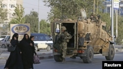 Arhiva - Avganistanka hoda dok britanski vojnici stižu na mesto eksplozije u Kabulu, Avganistan, 22. avgusta 2015.