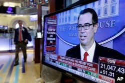 Treasury Secretary Steven Mnuchin appears on a television screen on the floor of the New York Stock Exchange, April 26, 2017.