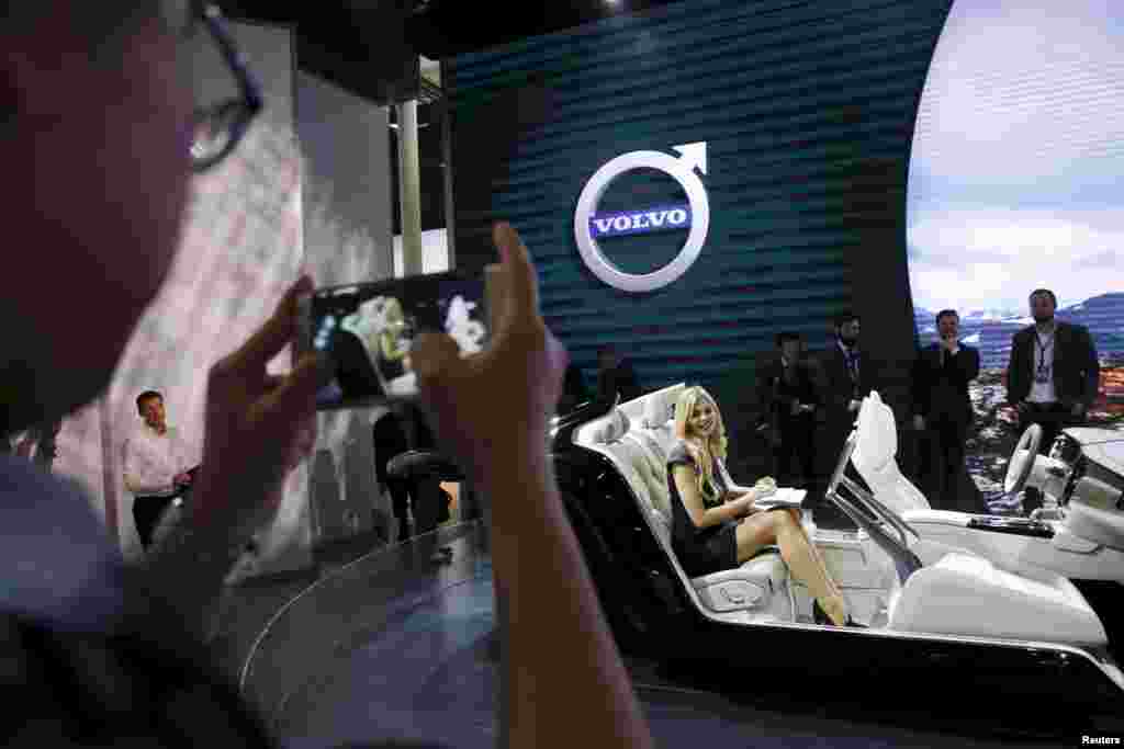 A girl types on a computer as she demonstrates the interior of the new Volvo S90 during the Auto China 2016 auto show in Beijing.