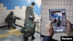 Seorang pria memotret tentara-tentara Korea Selatan dengan iPadnya pada saat latihan anti-teror dan keamanan di stasiun bawah tanah di Seoul, April 2013. (Reuters/Kim Hong-Ji)