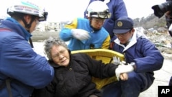 Eighty-year-old Sumi Abe is helped by emergency workers after being rescued from under the rubble in Ishinomaki City, Miyagi Prefecture, northern Japan, March 20 , 2011