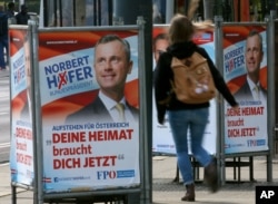 FILE - A woman walks past election posters of Norbert Hofer, candidate for presidential elections of Austria's right-wing Freedom Party, FPO, in Vienna, Austria, April 19, 2016.