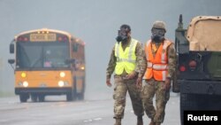 Tentara-tentara dari Garda Nasional Hawaii mengenakan masker untuk melindungi diri dari abu vulkanis dari letusan Gunung Kilauea di Hawaii, yang masih terus berlangsung, 17 Mei 2018.