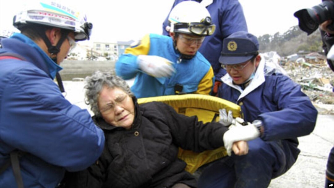 Eighty-year-old Sumi Abe is helped by emergency workers after being rescued from under the rubble in Ishinomaki City, Miyagi Prefecture, northern Japan, March 20 , 2011
