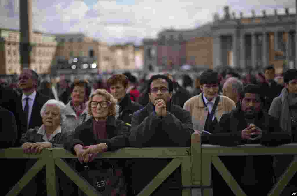 Faithful follow a Mass taking place inside St.Peter&#39;s Basilica for the election of a new pope, broadcast on a giant screen, not pictured, in St. Peter&#39;s Square, at the Vatican, March 12, 2013.