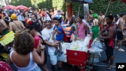 Revelers mill about as vendors with coolers filled with ice cold drinks wait for customers at the Heaven on Earth pre-Carnival street party, in Rio de Janeiro, Feb. 22, 2025.