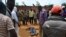 FILE - Civilians gather to look at the dead body of an unidentified man killed during fighting between the army and militia fighters in Beni, eastern Democratic Republic of the Congo, June 22, 2017.