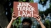 FILE - An activist holds a placard at a protest few hours before the start of the hearing of oral arguments on the anti-terrorism law, in front of the Philippine General Hospital, in Manila, Philippines, Feb. 2, 2021.