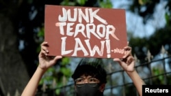 FILE - An activist holds a placard at a protest few hours before the start of the hearing of oral arguments on the anti-terrorism law, in front of the Philippine General Hospital, in Manila, Philippines, Feb. 2, 2021.