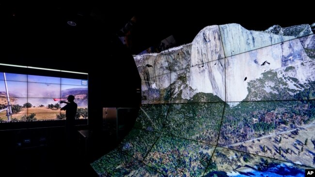 Falco Kuester, a researcher at ALERTCalifornia, a program run by the University of California San Diego, looks at imagery of firefighters at a fire from one of the program's cameras, alongside a digital rendering of Yosemite Valley, Sept. 18, 2023, in San Diego.