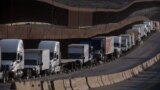 (FILE) Trucks queue next to the border wall before crossing to the United States at Otay commercial port in Tijuana, Baja California state, Mexico, on Jan. 22, 2025. 