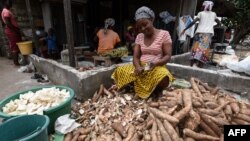 Une femme épluche des couches extérieures de manioc pour le plat d'accompagnement, attiéké, à Abidjan, le 22 mai 2018.