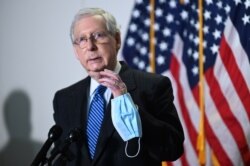 FILE - Senate Majority Leader McConnell holds a face mask while participating in a news conference at the U.S. Capitol in Washington, Oct. 21, 2020.