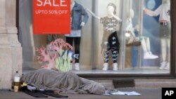 A homeless person sleeps in front of a closed clothing shop in London, Thursday May 14, 2020, as the country continues in lockdown to help stop the spread of coronavirus. Some of the coronavirus lockdown measures are being relaxed in England, after…