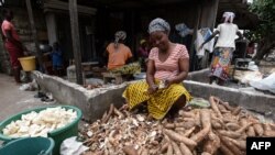 Une femme épluche des couches extérieures de manioc pour le plat d'accompagnement, attiéké, à Abidjan, le 22 mai 2018.