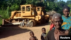 Congolese people standing in front of two bulldozers in Yayolo, Democratic Republic of Congo, October 2004. (file photo)