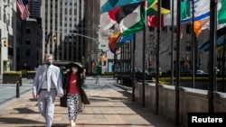 마스크를 착용한 남녀가 신종 코로나바이러스로 한산한 뉴욕 맨해튼 도심을 걷고 있다.