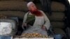 FILE - A man sporting a henna-dyed beard fans himself as he sells lumps of brown sugar at the market in Peshawar, Pakistan, June 30, 2017. 