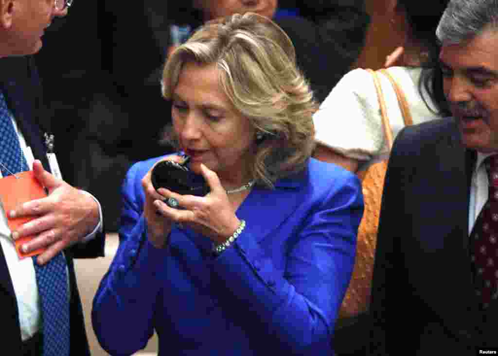 Clinton pauses to put on lipstick while talking with Turkey's President Abdullah Gul (R) at the start of a United Nations Security Council meeting at the U.N. headquarters in New York, September 23, 2010.