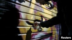 Artist Solomon Souza,22, spray-paints a portrait on the metal shutter of a closed storefront in Mahane Yehuda, one of Jerusalem's most popular outdoor markets, Feb. 24, 2016. 