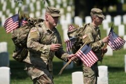 Ahead of Memorial Day, members of the U.S. armed forces place flags in front of more than 260,000 headstones at Arlington National Cemetery, in Arlington, Virginia, May 27, 2021.